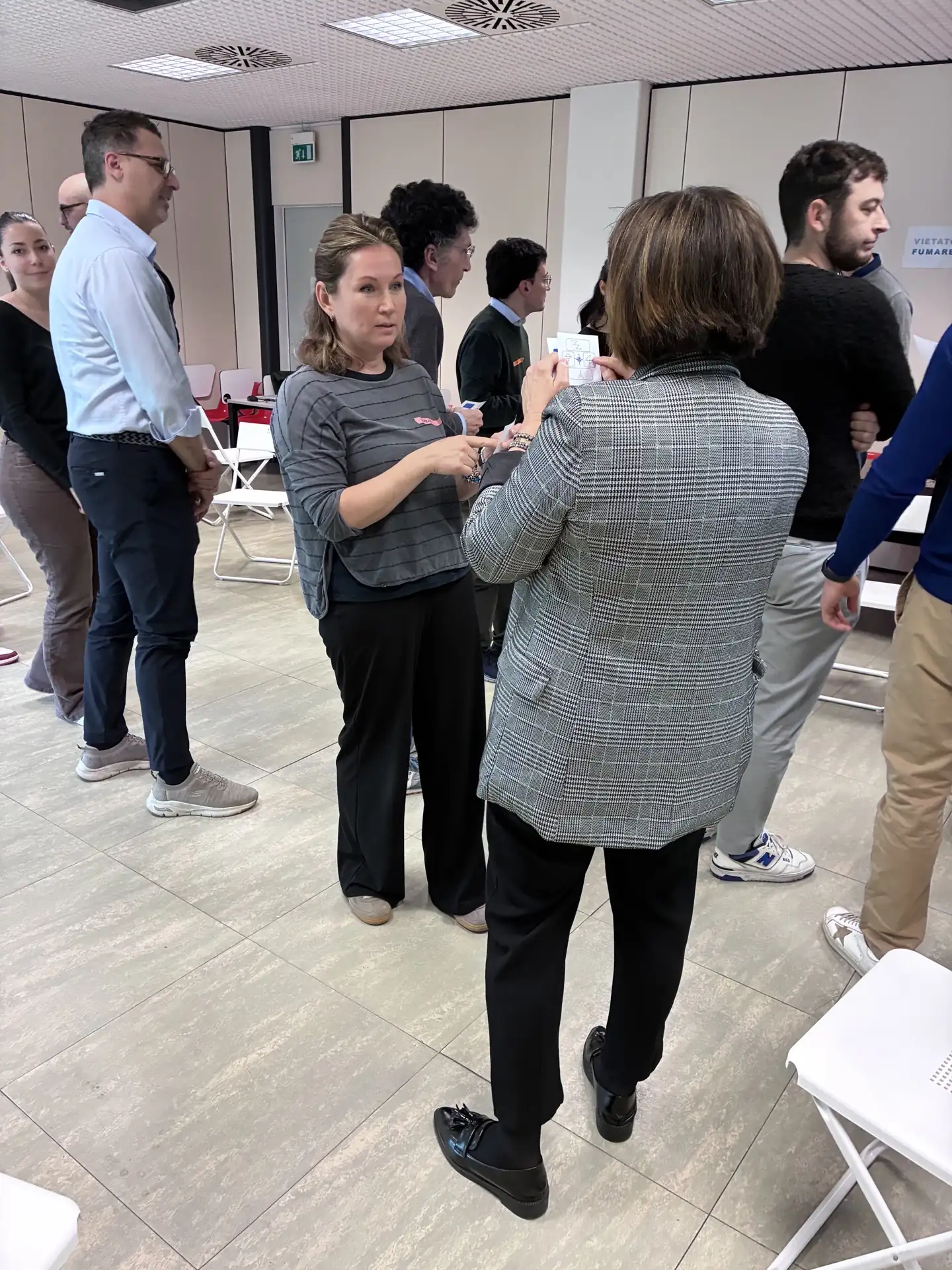 Due partecipanti si confrontano utilizzando una scheda illustrata durante un esercizio di feedback e problem solving.