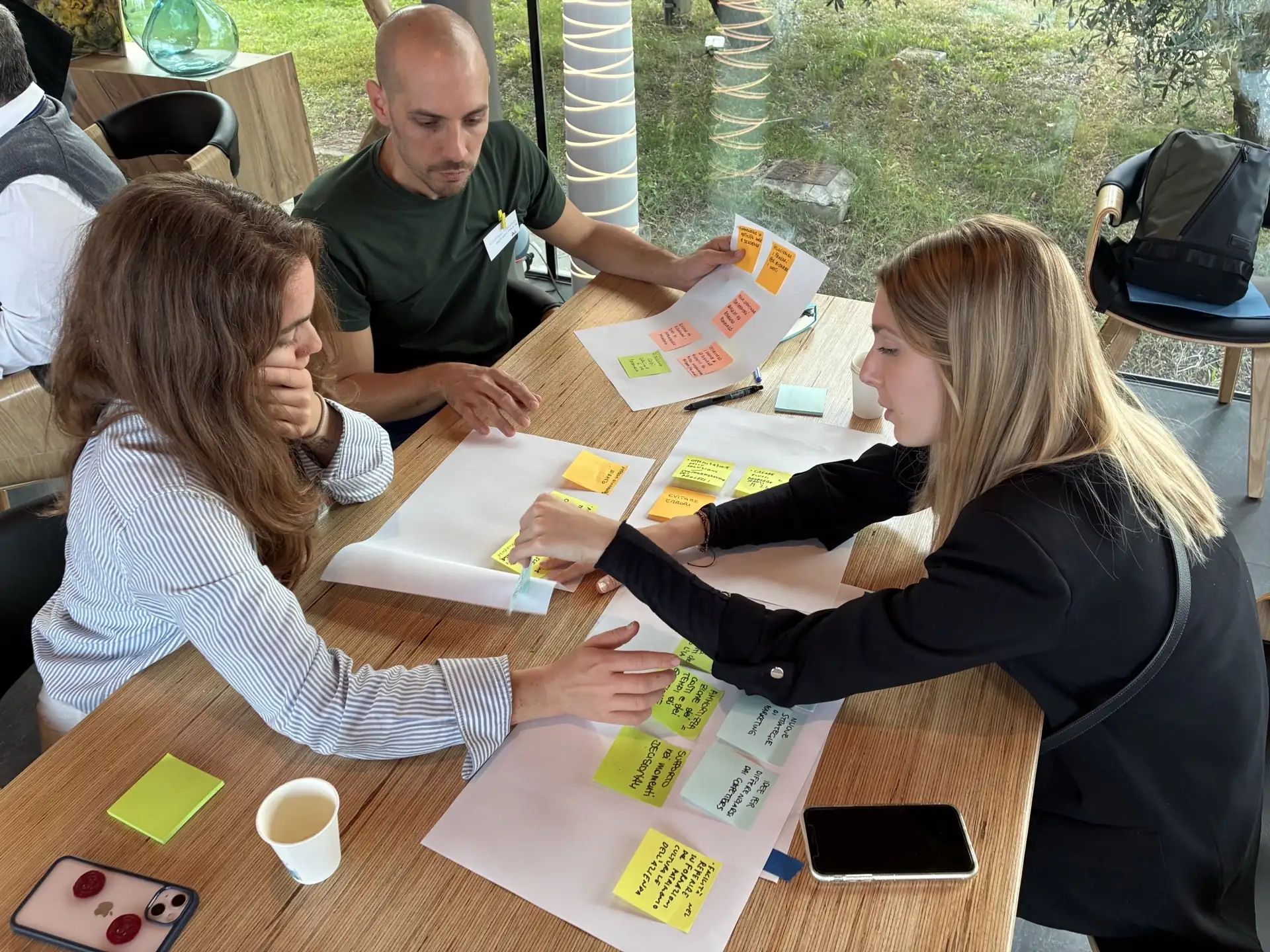 Tre partecipanti organizzano con post-it le esperienze e i contributi raccolti sull’utilizzo dell’intelligenza artificiale nelle aziende.